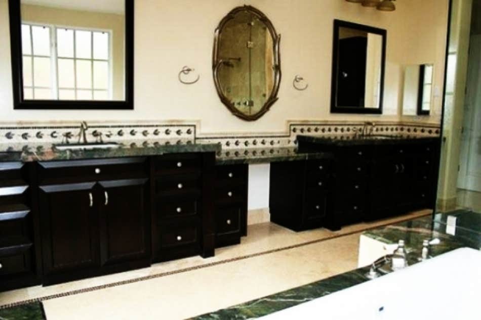 Bath with double dark vanities and green marble counters